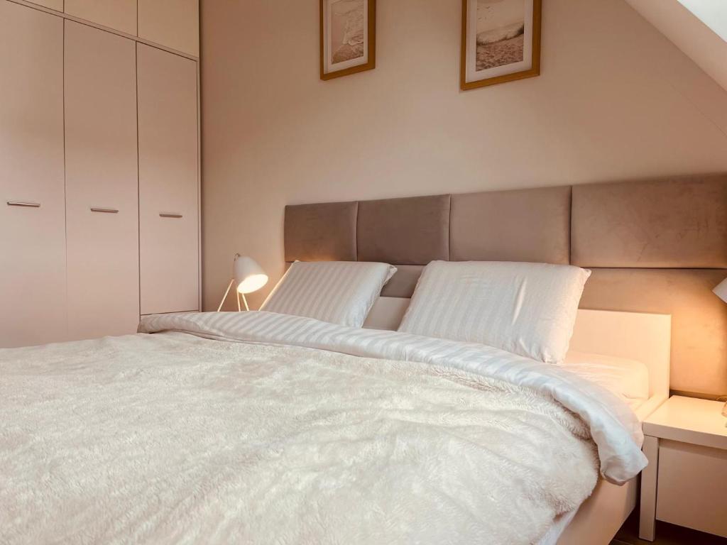 Apartament Kołobrzeg Lwowska 12B - główna sypialnia z szarym zagłówkiem, białą pościelą i wbudowanymi szafami