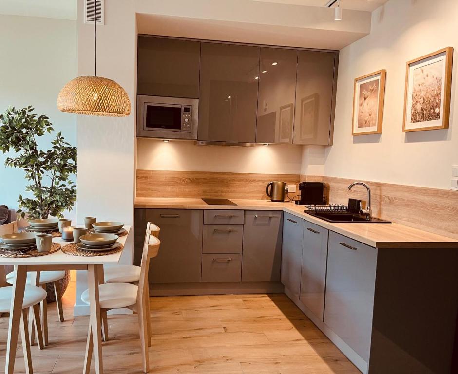 Apartament Boho Podczele - w pełni wyposażona kuchnia z szarymi frontami, drewnianym blatem i lampą rattanową
