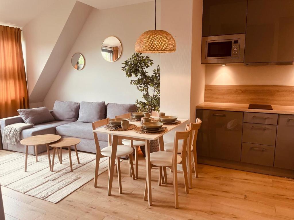 Apartament Boho Podczele Kołobrzeg Lwowska 12B - salon z kuchnią w stylu boho z szarą sofą i nowoczesną kuchnią